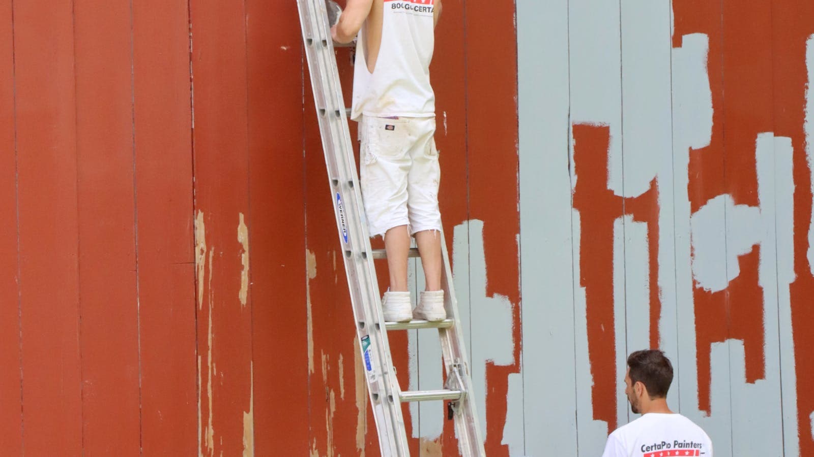 Professional painters on ladders applying fresh exterior paint to a two-story wood-sided home in Vancouver, WA