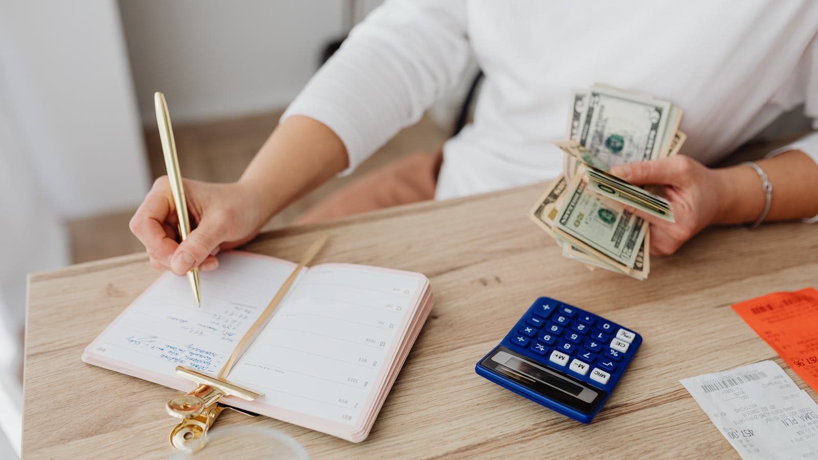 Homeowner using a calculator and writing in a planner with cash on the table while planning a Vancouver, WA remodel budget and contingency